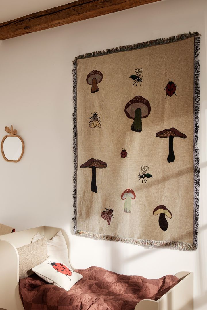 A children's room decorated with motif's of mushrooms with a wall hanging from Ferm Living - highlighting nature as one of the Scandinavian  interior design trends for 2023.